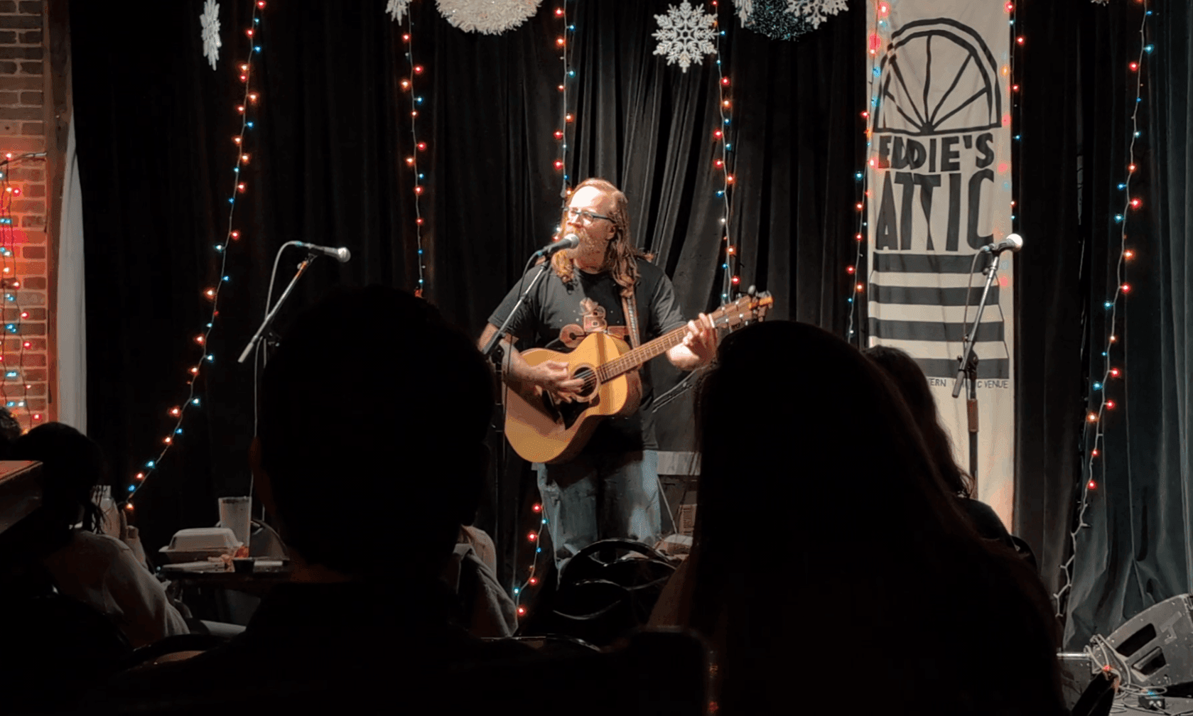 a man playing an acoustic guitar in front of a crowd